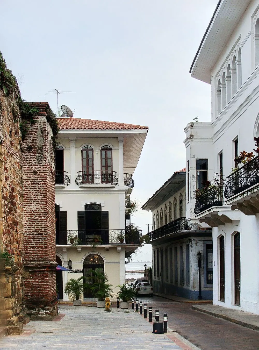 Calle del Casco Antiguo con casas coloniales blancas de balcones de hierro y un muro de piedra